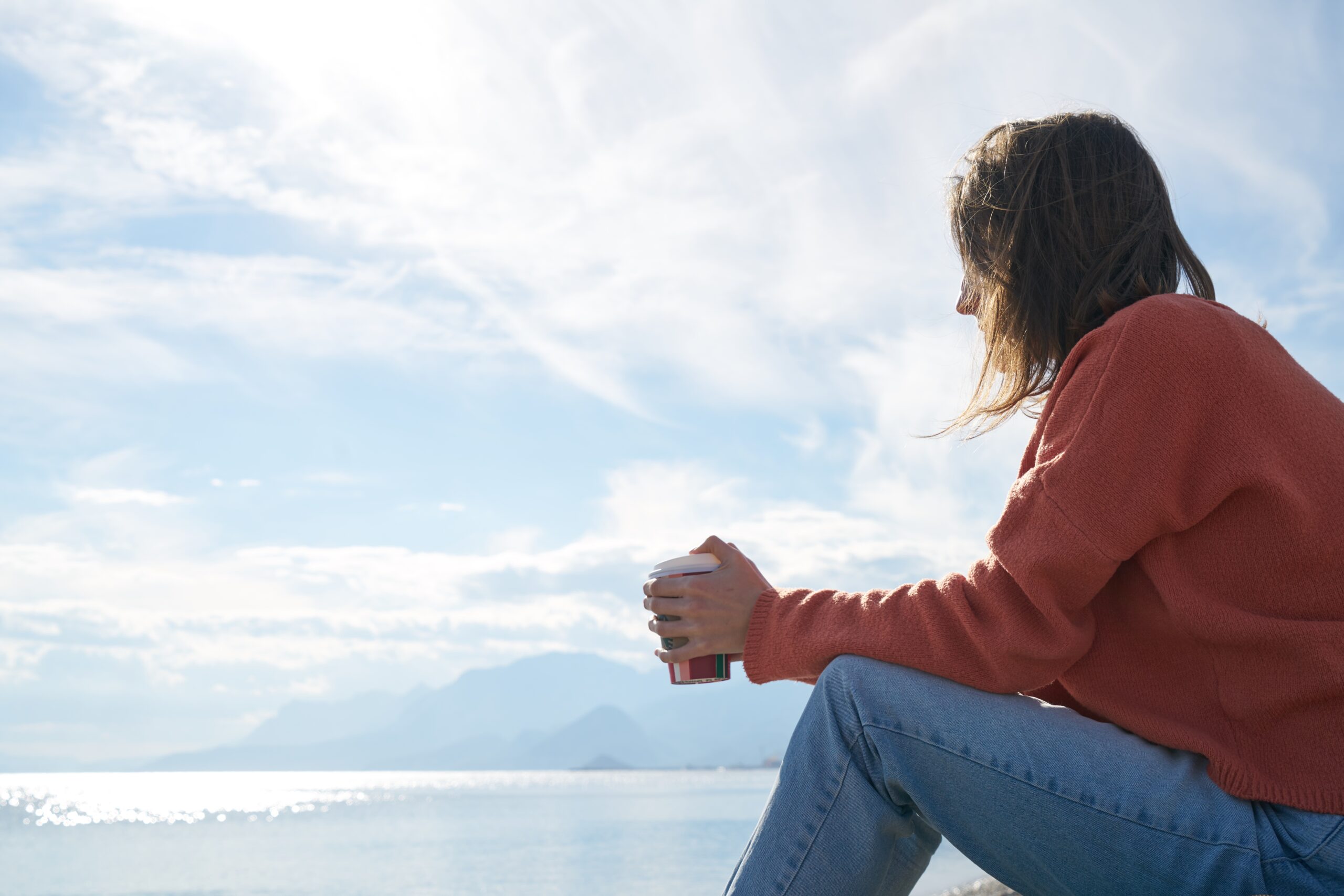 woman sitting in front of body of water 2174625 scaled