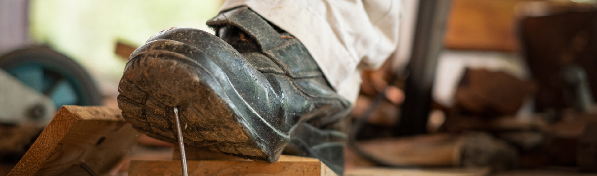 Close up of a Workman stepping on a nail on a worksite that pierces his boot sole - Panama City Work Injury Attorney