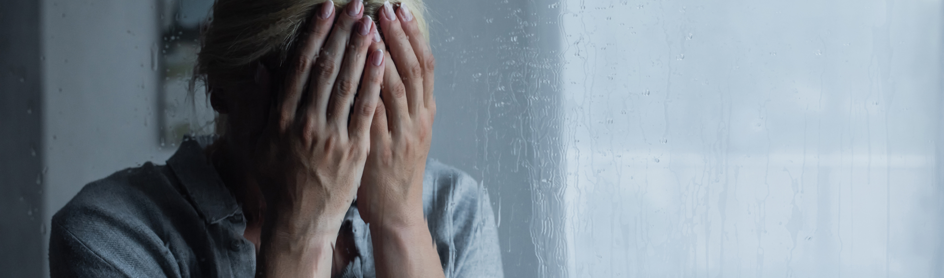 depressed blonde woman covering face behind wet window with rain drops banner